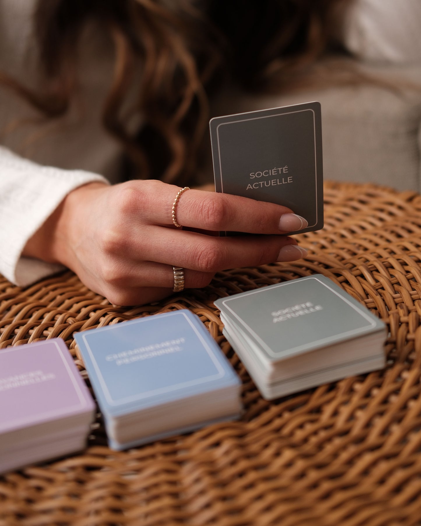 Hand holding a card with ‘societe ACTUELLE' text on a woven surface.